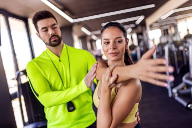 Kişisel antrenörün portresi müşterilerinin kol pozisyonunu ayarlıyor..  