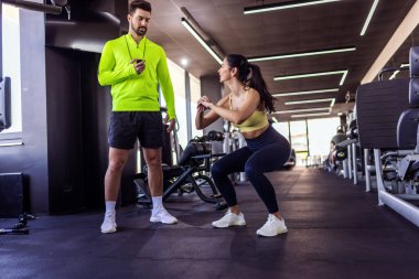 Kişisel antrenör portresi çömelme yapan bir kıza sayım yapıyor..