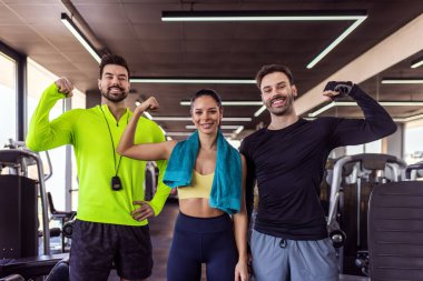 Spor salonundaki üç zinde insan kollarını esneterek poz veriyor..