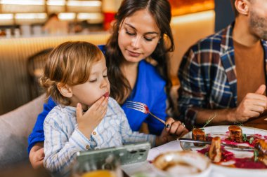 Üç kişilik bir aile lezzetli bir restoranda yemek yiyor. Yiyecek ve içecek konsepti.