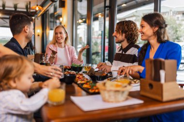 Aile ve arkadaşlar lezzetli yemekler yemek, konuşmak, içmek ve takılmak için bir restoranda toplandılar..
