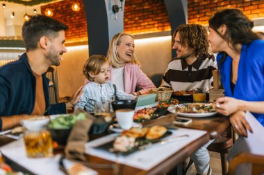 Aile ve arkadaşlar lezzetli yemekler yemek, konuşmak, içmek ve takılmak için bir restoranda toplandılar..