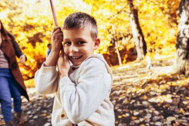 Mutlu aile sonbahar parkında salıncakta sallanırken eğleniyor..