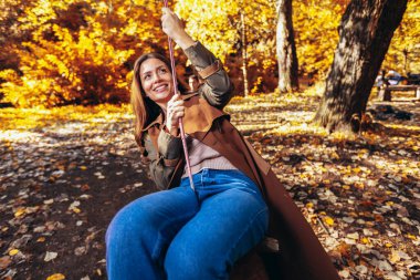 Mutlu aile sonbahar parkında salıncakta sallanırken eğleniyor..