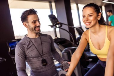 Spor salonunda özel antrenörü onu cesaretlendirirken bisiklet süren bir kadın..