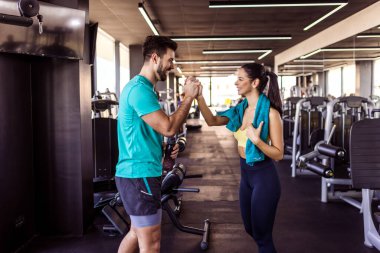 Spor salonunda iyi bir antrenmandan sonra iki fit insan beşlik çakar..