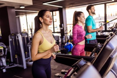 İnsanlar spor salonunda koşu bandında koşuyor..