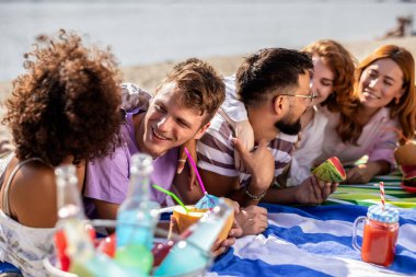 Beş tane çok ırklı arkadaş kumsalda piknik yapıyor. Karpuz yiyorlar, renkli kokteyller içiyorlar ve yanlarında gitarları var..