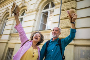 Şehir merkezinde mutlu mesut ayakta duran yaşlı evli bir çift. Havaya şapka atmak..