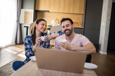 Çift kahve içer ve laptoplarını oturma odasının zemininde kullanır..