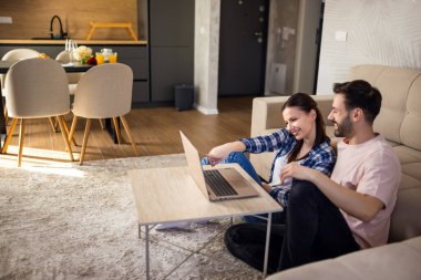 Çift, evlerinin oturma odasında otururken dizüstü bilgisayar kullanıyor..