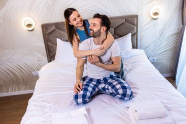 Genç mutlu çift yatakta. Kız arkadaşı erkek arkadaşına arkadan sarılıyor. Birbirlerine bakıyorlar..