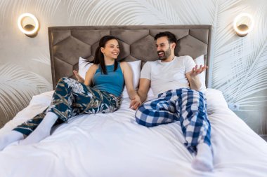 Sevimli genç çift yatakta el ele tutuşup konuşuyor..