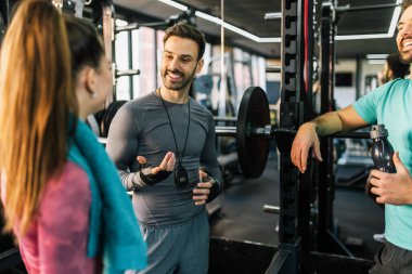 Spor salonunda üç atletik insan setlerinin arasında konuşuyor..