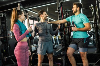 Spor salonunda üç atletik insan setlerinin arasında konuşuyor..