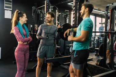 Spor salonunda üç atletik insan setlerinin arasında konuşuyor..