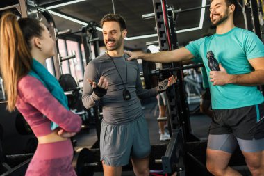 Spor salonunda üç atletik insan setlerinin arasında konuşuyor..