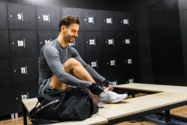 Formda adam ayakkabılarını spor salonunun soyunma odasına bağlıyor..