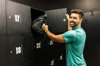 Formdaki adam eşyalarını spor salonunun soyunma odasındaki dolaba koyar..