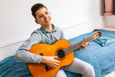Küçük çocuk evde klasik gitar çalıyor..
