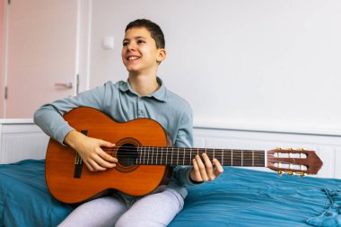 Küçük çocuk evde klasik gitar çalıyor..