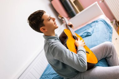 Küçük çocuk evde klasik gitar çalıyor..