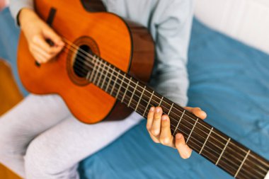 Küçük çocuk evde klasik gitar çalıyor..