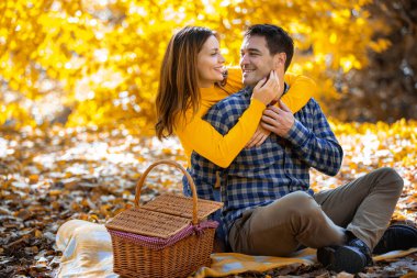Evli çift sonbahar günü parkta piknik yapar. Kadın kocasına sarılıyor..