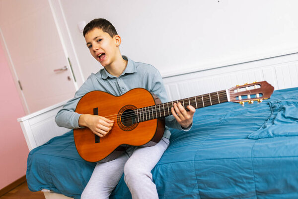 Little boy plays classical guitar at home.