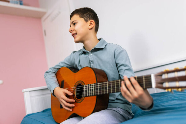 Little boy plays classical guitar at home.