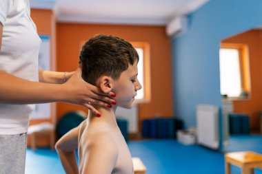 Küçük çocuğun terapi amaçlı kinezi terapisi. Omurga düzleştirme, skolyoz. Doktor ona yardım ediyor..