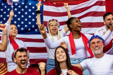 Amerikan futbolu ve futbol taraftarları stadyumda bayrak ve diğer ekipmanlarla tezahürat yapıyorlar.
