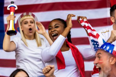 Amerikan futbolu ve futbol taraftarları stadyumda bayrak ve diğer ekipmanlarla tezahürat yapıyorlar.
