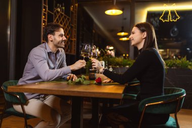 Erkek ve kadın romantik bir akşam yemeği sırasında restoranda beyaz ve kırmızı şarapla kadeh kaldırıyorlar..