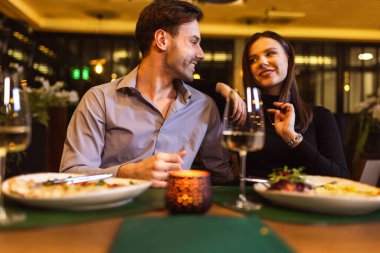 Mutlu çift şık bir restoranda romantik bir akşam yemeği yiyor. Lezzetli yemekler yiyorlar..