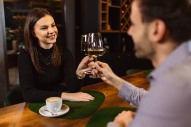 Erkek ve kadın romantik bir akşam yemeği sırasında restoranda beyaz ve kırmızı şarapla kadeh kaldırıyorlar..