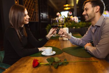 Erkek ve kadın romantik bir akşam yemeği sırasında restoranda beyaz ve kırmızı şarapla kadeh kaldırıyorlar..