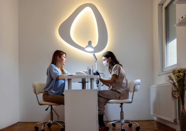 Güzellik salonunda elektrikli makine kullanan profesyonel bir manikürcü. Güzellik salonunda tırnaklarını yaptıran bir kadın..