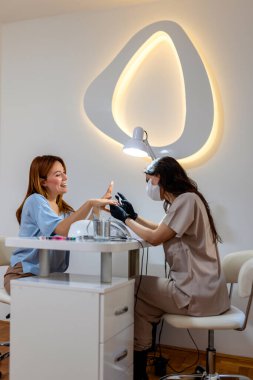 Manikürcü müşterinin tırnaklarını güzellik salonunda törpülüyor..