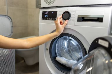 Modern otomatik çamaşır makinesinin el işletim düğmesini çalıştıran kesilen kadının görüntüsünü kapat.