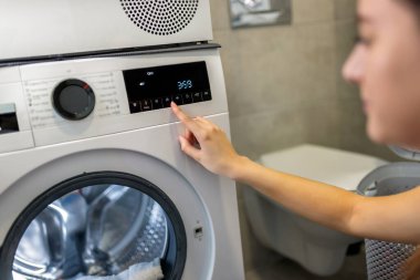 Modern otomatik çamaşır makinesinin el işletim düğmesini çalıştıran kesilen kadının görüntüsünü kapat.