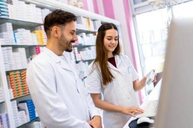 Tezgahta bilgisayar kullanan iki genç kadın eczacı..