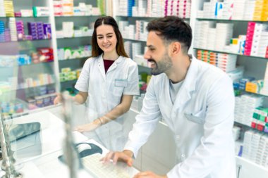 Tezgahta bilgisayar kullanan iki genç kadın eczacı..