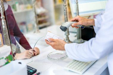 Eczanedeki kasiyer, barkod okuyucusuyla ilaçları tarıyor..