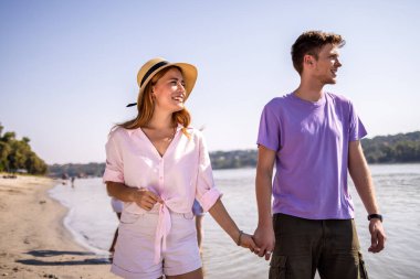 Genç bir çift kumsalda yürüyor, arkadaşlıklarından ve dalgaların sesinden keyif alıyorlar. El ele tutuşup gülümserler. Sahilde huzurlu ve romantik bir an yaşarlar..