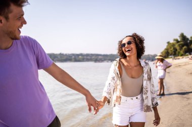 Genç bir çift kumsalda yürüyor, arkadaşlıklarından ve dalgaların sesinden keyif alıyorlar. El ele tutuşup gülümserler. Sahilde huzurlu ve romantik bir an yaşarlar..