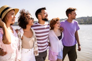 Beş genç arkadaştan oluşan bir grup kumsalda yürüyor, gülüyor ve deniz kenarında kaygısız bir günün tadını çıkarıyorlar.. 