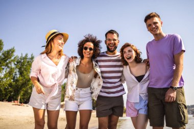 Beş genç arkadaştan oluşan bir grup kumsalda yürüyor, gülüyor ve deniz kenarında kaygısız bir günün tadını çıkarıyorlar.. 