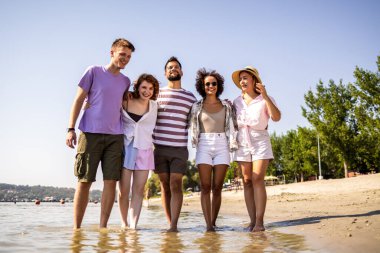 Beş genç arkadaştan oluşan bir grup kumsalda yürüyor, gülüyor ve deniz kenarında kaygısız bir günün tadını çıkarıyorlar.. 