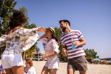 Canlı bir plaj partisinde kokteyl içen bir grup arkadaş. Arka planda müzik, renkli içecekler ve okyanusun üzerinde güneş batarken sahne enerji, eğlence ve yaz kutlamalarıyla dolu. Saf sahil titreşimleri ve gençlik sevinci.